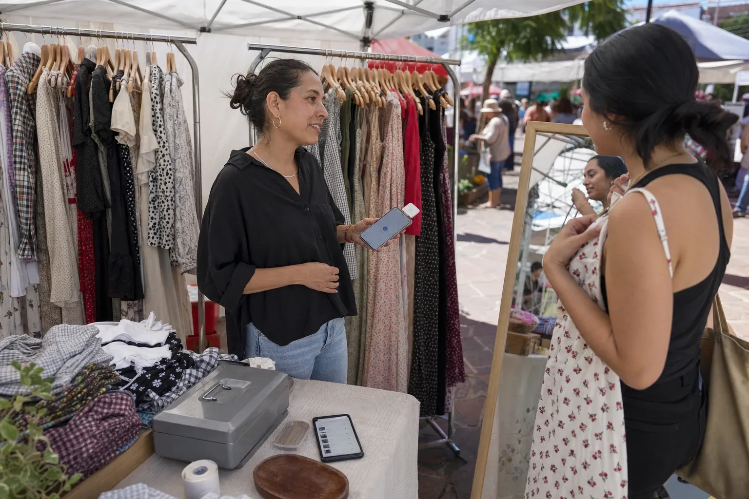 Puesto de bazar de fin de semana con los racks bajo la carpa, el espejo de cuerpo completo y el cobro desde el celular