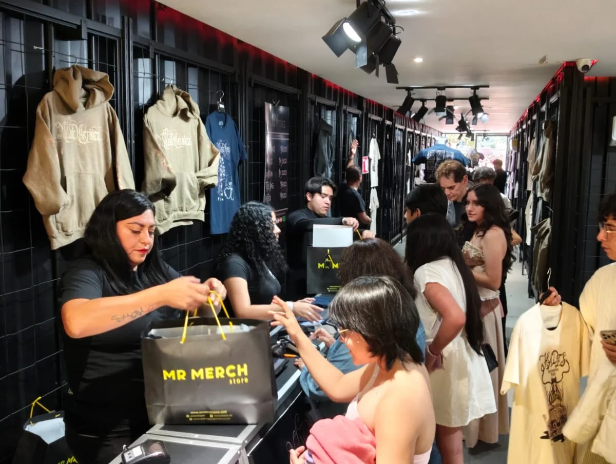 Equipo de Mr Merch entregando bolsas a fans en el mostrador