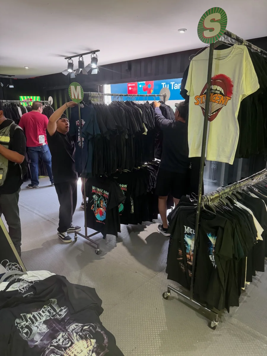 Equipo de Live Shows acomodando playeras de giras por talla en los racks de la tienda
