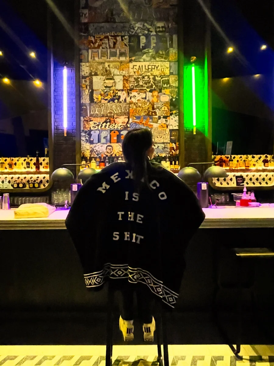 Mujer en la barra con el poncho «Mexico Is The Shit»
